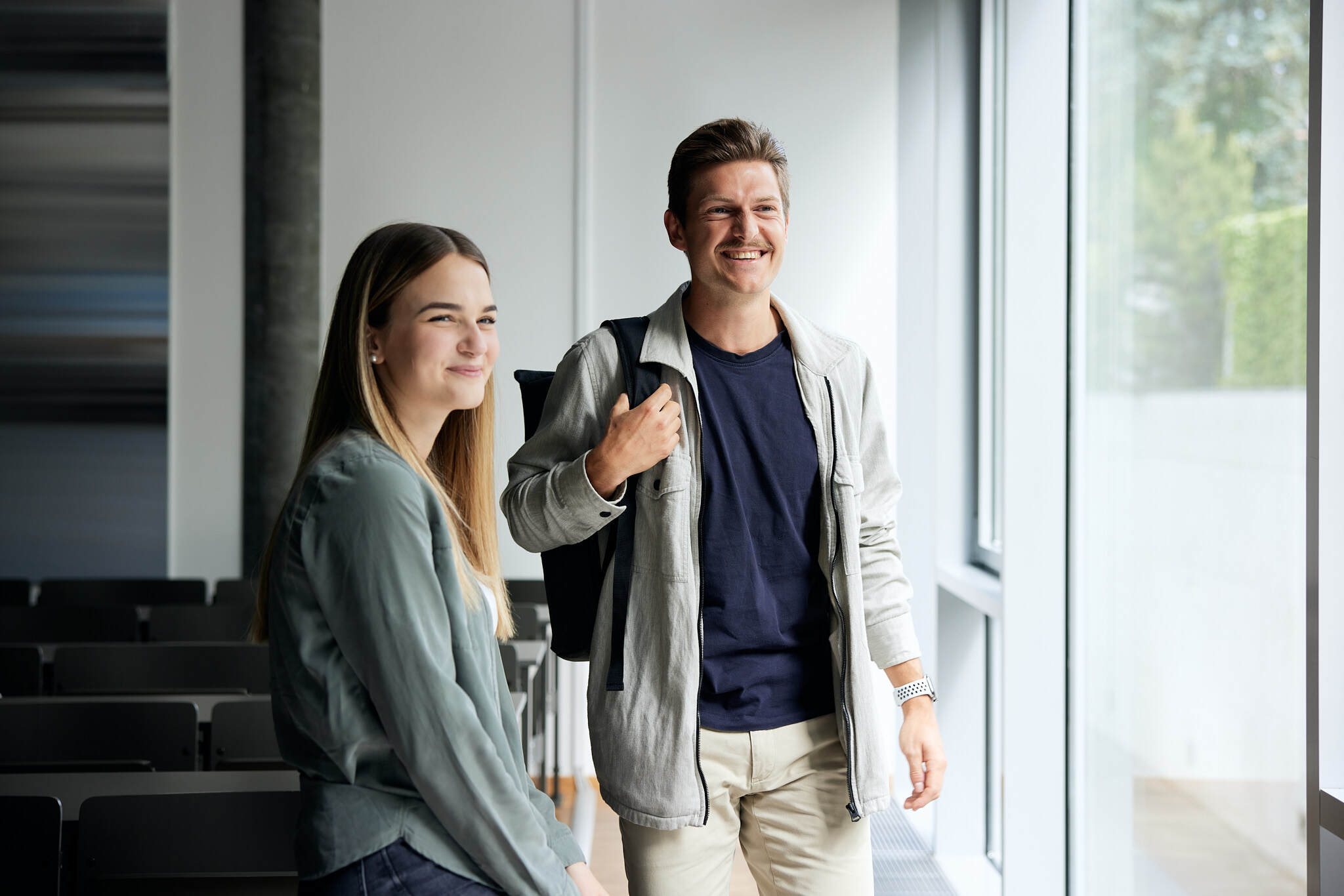 Zwei junge Studenten stehen neben einander vor einem Fenster in einer Klasse der FH Wels