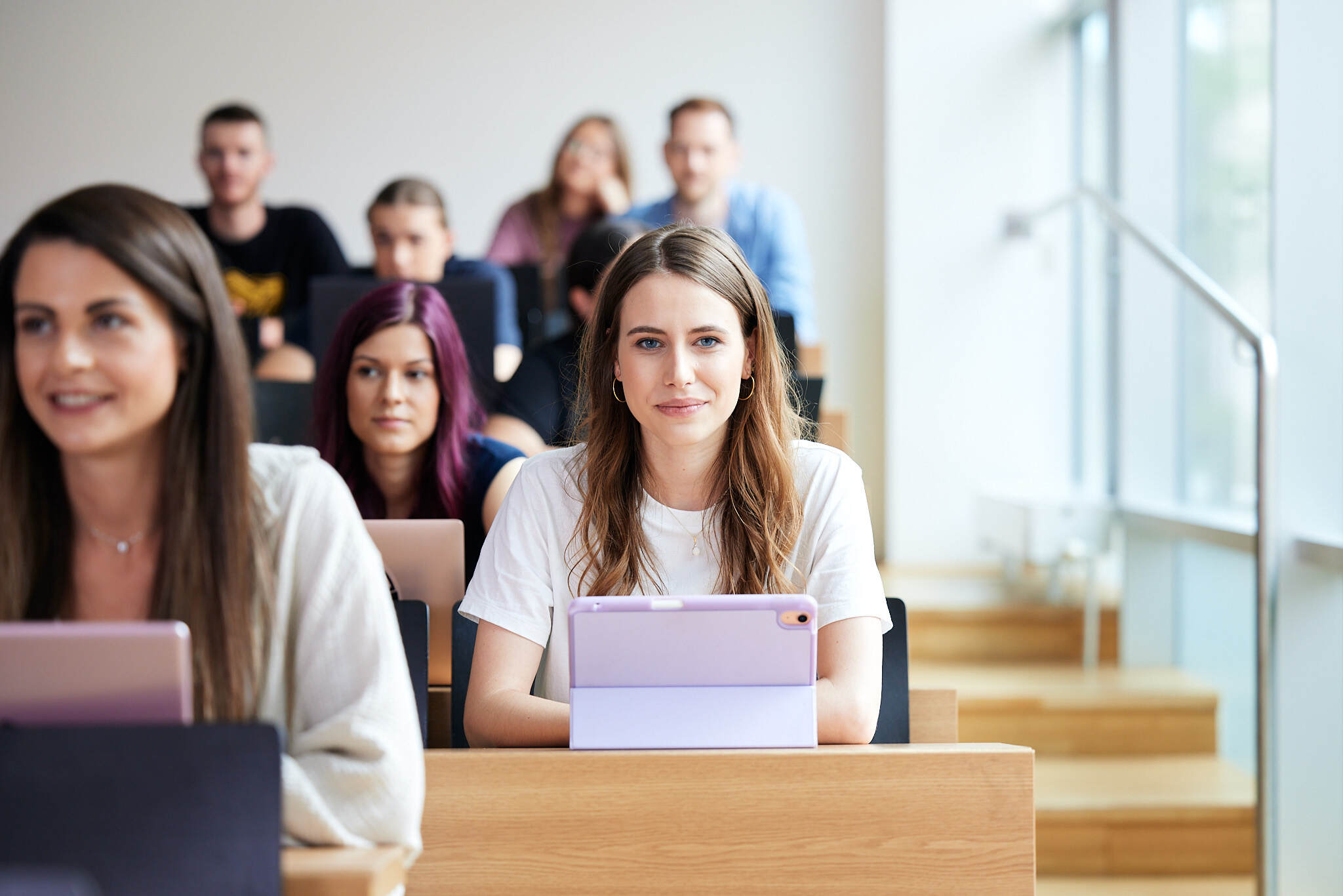 Im Fokus liegt ist eine junge Studentin in einem Hörsaal der FH Linz und blickt nach vorne, während die anderen Studentin unscharf sind