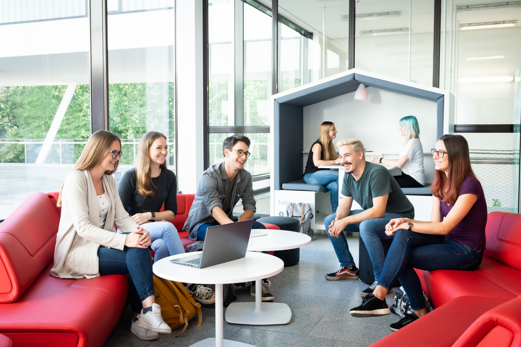 5 Studierende sitzen auf einer Couch und unterhalten sich angeregt.