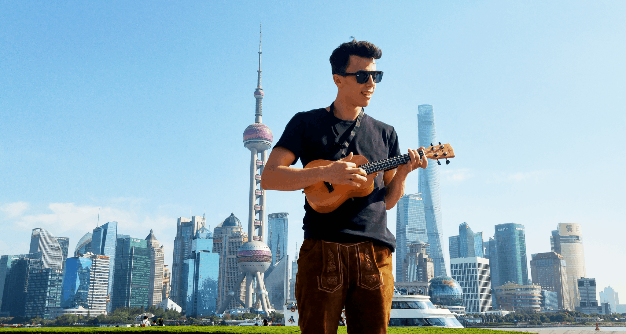 Ein junger Student spielt Ukulele vor der Skyline von Shanghai